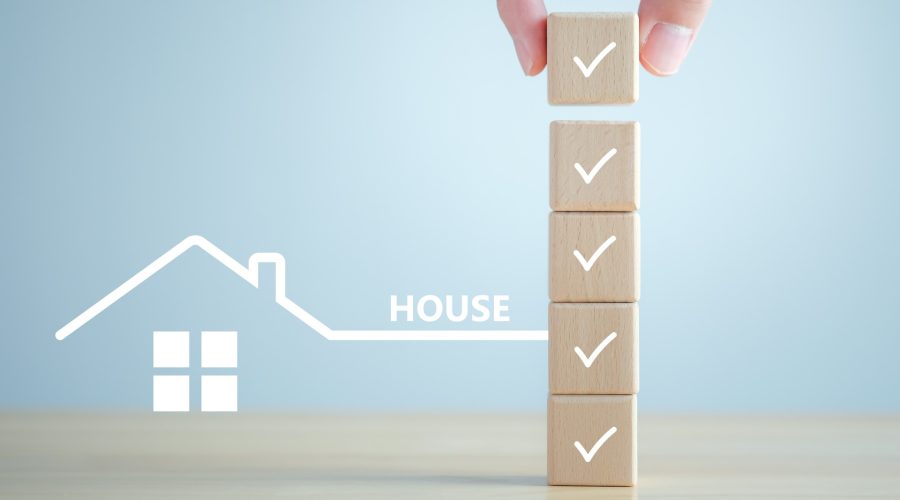 Illustration of a house outline connected to a vertical checklist of wooden blocks with checkmarks on a light blue background.