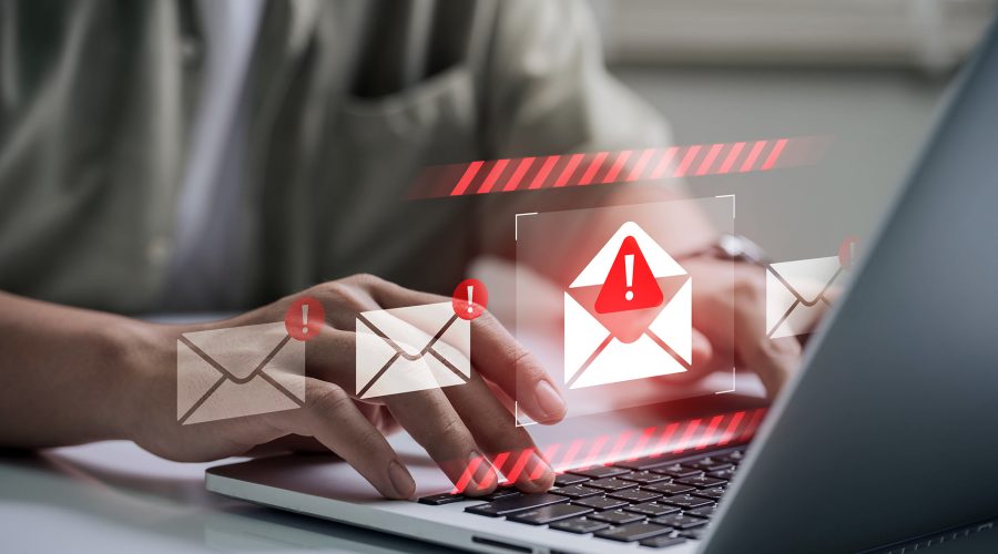 Hands typing on a laptop with envelope icons and red exclamation marks—phishing email warning.