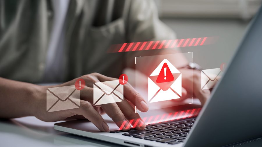 Hands typing on a laptop with envelope icons and red exclamation marks—phishing email warning.
